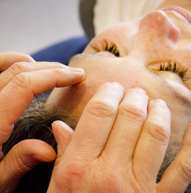 Hands holding acupressure points on a woman's forehead